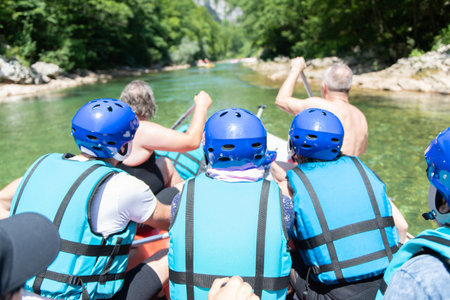 Close up of rafting team goes down the river on the beautiful sunny day. Back view.