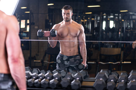 Sexy muscular man doind biceps exercise and looking at the mirror