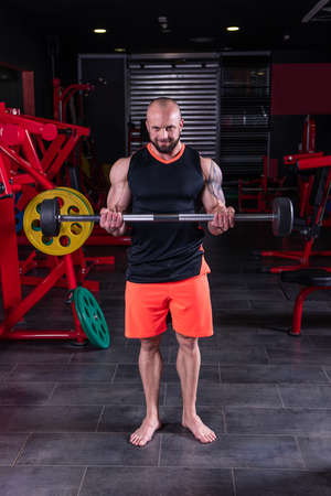 Powerful muscular man doing biceps exercise with barbell at the gymの写真素材