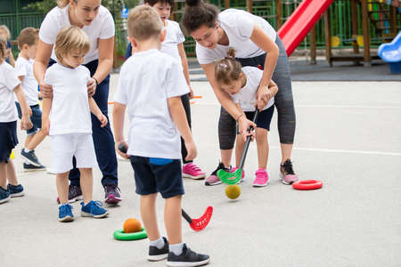 Group of children playing hockey within polygon.  Sport school. Coach helpingの写真素材