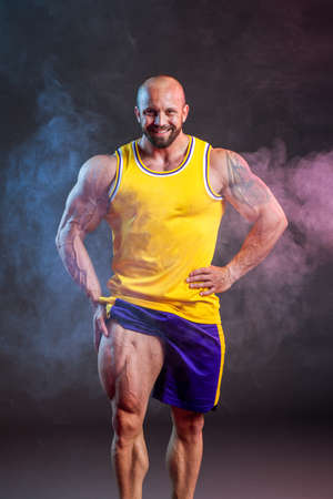 Powerful muscular man posing in the studio with red and blue smoke. Quadriceps contractionの写真素材