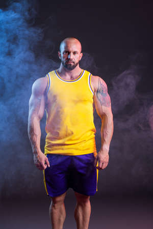 Powerful muscular man posing in the studio with red and blue smokeの写真素材