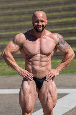 Powerful muscular bodybuilder in panties posing at the park.  Quadriceps and upper body contractionの写真素材