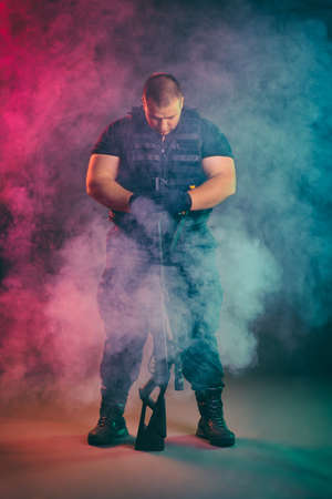 Soldier comes out of the smoke on the battlefield. The concept of military special operations. Standing and posing with shotgunの写真素材