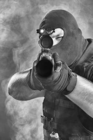 Soldier comes out of the smoke on the battlefield. The concept of military special operations. Aim at the target. Black and white colorの写真素材
