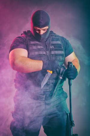 Soldier comes out of the smoke on the battlefield. The concept of military special operations. Posing with knife and shotgunの写真素材