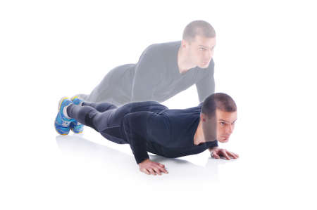 Concentrated young sportsman exercising and doing push ups on the white background. Studio shootの写真素材