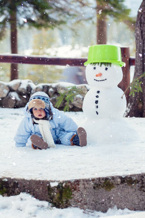 Beautiful baby boy sitting on the snow and posing. Winter season.の写真素材