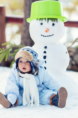 Beautiful baby boy sitting on the snow and posing. Winter season.の写真素材