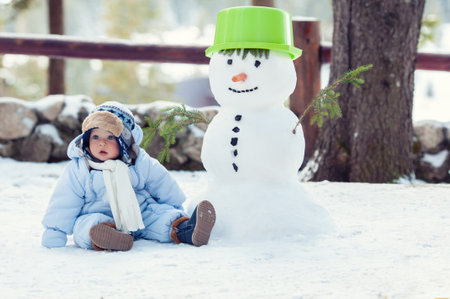 Beautiful baby boy sitting on the snow and posing. Winter season.の写真素材