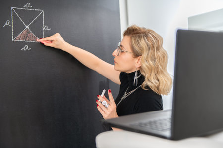 Young female math teacher explaining geometry on the black wall.