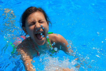 young girl playing in the poolの写真素材