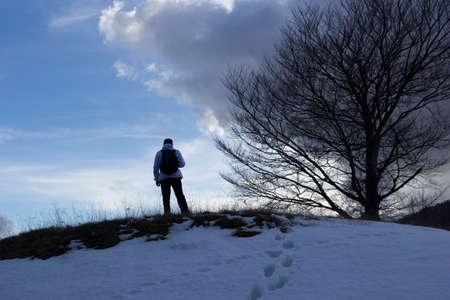 Hiker on the summit of a mountain with snowの写真素材