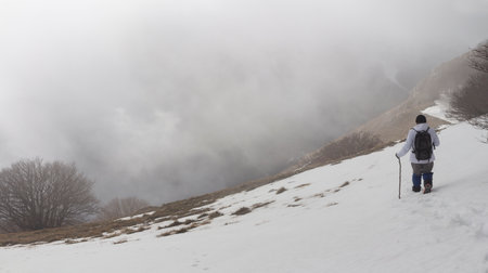Hiker on the summit of a mountain with snowの写真素材
