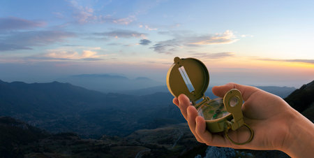hand with compass and sunset in the mountains for backgroundの写真素材