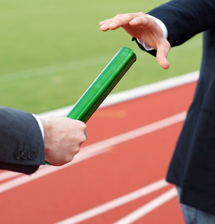 Businessmen passing baton in relay raceの写真素材