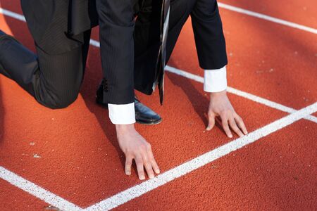 Business man waiting for start signal to run on the competition running trackの写真素材