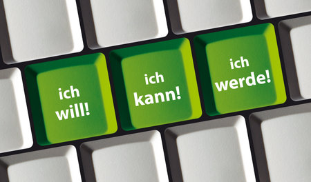 A closeup photo of a keyboard featuring motivational German phrases I want, I can, I will on its...