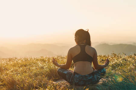 A young athletic woman practicing meditation outdoors during sunsetの写真素材