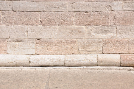 Pedestrian walkway in front of old stone wall 