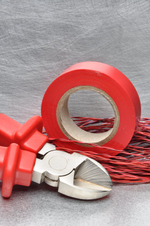Red electrical tools and cables on metal surface with place for text