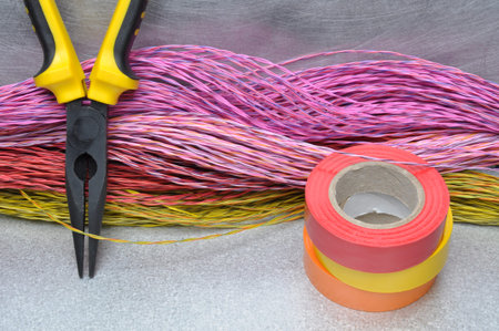 Multicolored pliers, insulating tapes and cables on metal surface