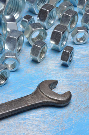 Old wrench and group of nuts on blue metal backgroundの写真素材
