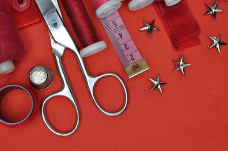 Sewing kit tool, scissors, thread and accessories on a red backgroundの写真素材