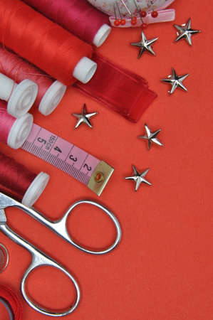 Sewing kit tool, scissors, thread and accessories on a red backgroundの写真素材