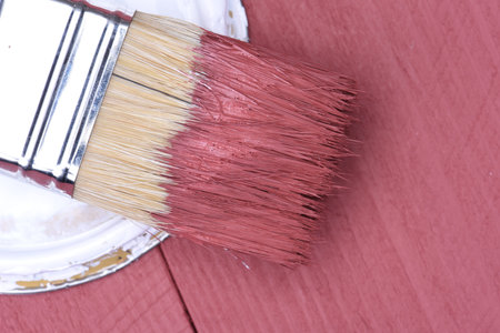 Pink paint can with brush on wooden background
