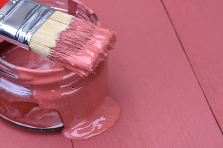 Pink paint can with brush on wooden background