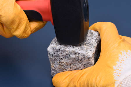 Close-up of a hand holding a hammer and stone blockの写真素材