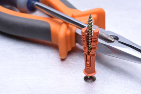 Pliers, screwdriver and dowel on metal backgroundの写真素材