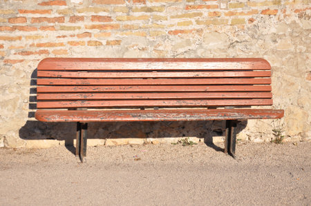 Wooden bench against a stone wallの写真素材