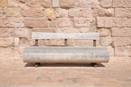 Wooden bench against a stone wallの写真素材
