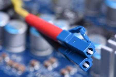 Fiber Optical Network Cables Close-up with Electronic Board in Backgroundの写真素材