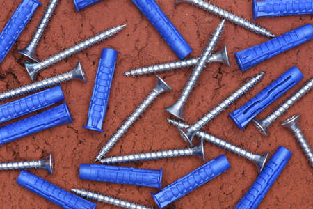Plastic Dowels ans Screws on Red Brick Background Top Viewの写真素材