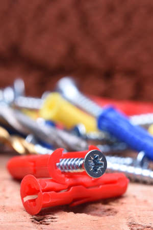 Screws plasctic dowels and tool on brick background close-upの写真素材