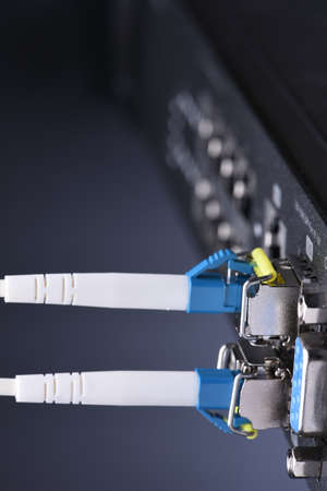 Network devices technology, optical fiber cable and switch, close-up on black backgroundの写真素材