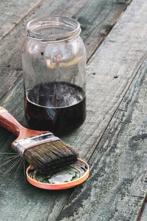 Brush and jar of paint on wooden boardの写真素材
