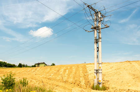 High-voltage power lines on field against blue skyの写真素材
