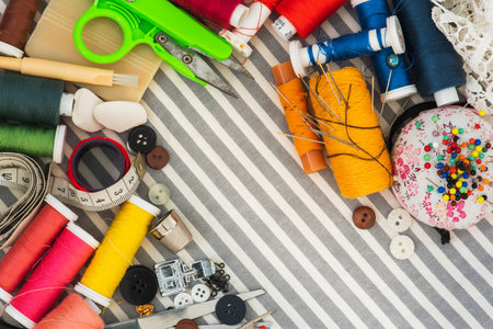 Sewing tools on striped background top view