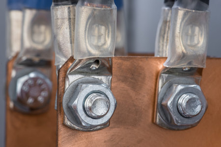 Joint of electric cable with copper busbar by bolts and nuts in electrical power supply switchboard