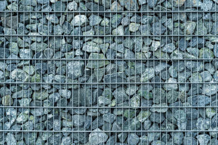 Retaining wall made of stacked stone-filled gabion tied together with wire, natural backgroundの写真素材