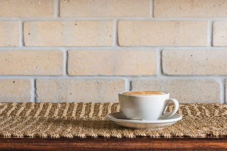 Coffee Cappuccino on Table with Brick Wall Backgroundの写真素材