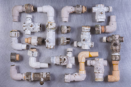 Old plumbing water fittings on gray metal surface, directly above view