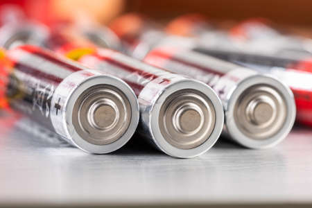 Macro of AA alkaline batteries lying on metal table with blurred energetic backgroundの写真素材