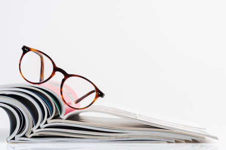 Open magazine with reading glasses on topの写真素材
