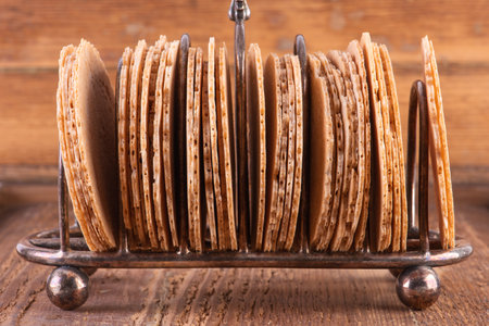 Sterling Silver Toast Rack with Thin Round Biscuits On Wooden Board Tableの写真素材