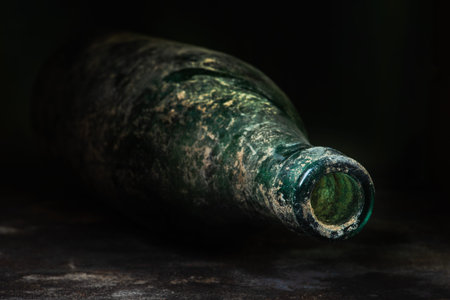 Dirty empty glass beer bottle lying in darkness